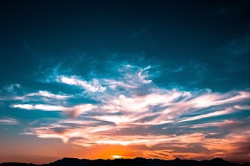 mountains under cloudy skies during golden hour