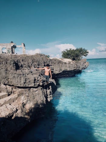 Msn Standing Beside Gray Rock Formation Beside Body of Water