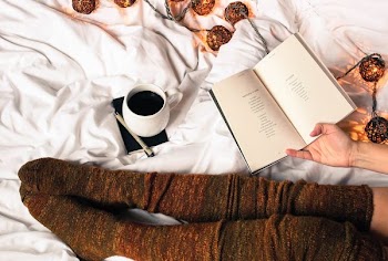 mug of black coffee beside person's feet wearing brown stockigns