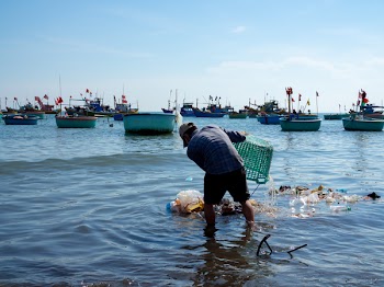 Mui Ne, VIETNAM - Aril 30, 2018: The Man Dumb Trash into The Sea in Fisherman Village, Mui Ne, Vietnam