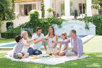 Multi-generation family enjoying picnic in sunny backyard