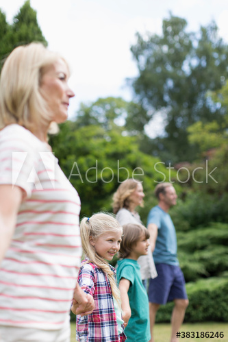 Multi-generation family holding hands in backyard