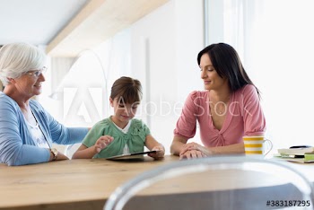 Multi-generation family using digital tablet at dining table