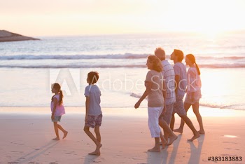 Multi-generation family, walking on beach at sunset