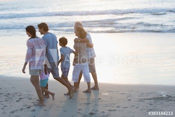 Multi-generation family walking on sunset beach