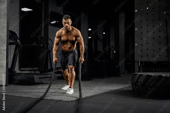 Muscular caucasian man training with ropes.