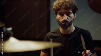 Musician playing on drum kit in studio. Artist jumping during repetition indoor.