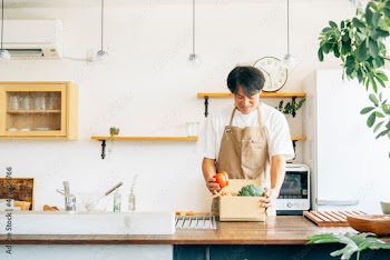 キッチンでダンボールに入った野菜を持つ男性
