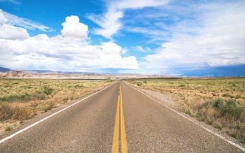 narrow road under cloudy skies at daytime