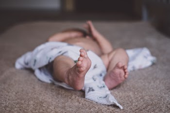 Newborn baby lying down on the mattress