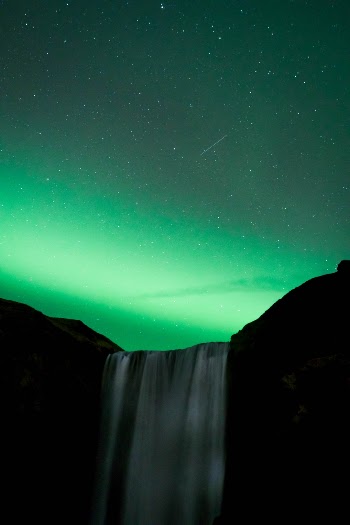 Northern lights over waterfall with sooting star