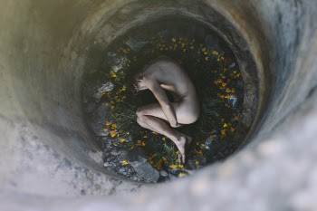Nude Person Inside Well Laying on Flowers