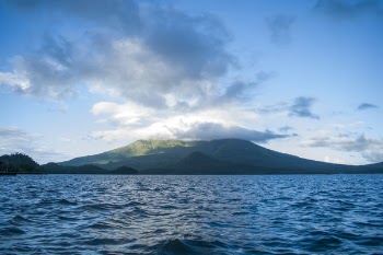 Ocean Near High Rise Mountain Cover With Fogs at Daytime