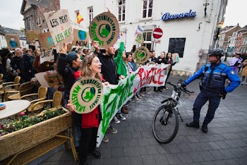 Officer Standing Beside Bike and People With Signs