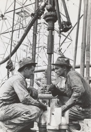 Oil drillers talking with bits in front of them and drilling equipment in background, Kilgore, Texas.
1939, photographer Lee Russell