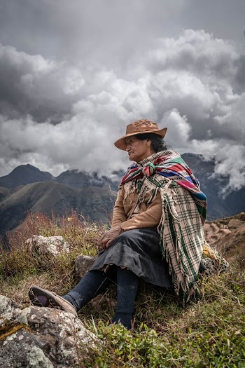 Old Woman Sitting on a Rock In  Brown Grass Field