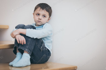 one sad little boy sitting on the stairs in house at the day tim ...