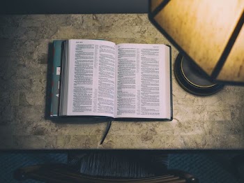 open white and blue book beside table lamp