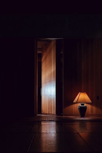 opened brown wooden door near table lamp