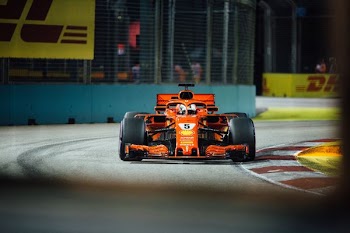 orange and black racing car near grey metal rails at daytime