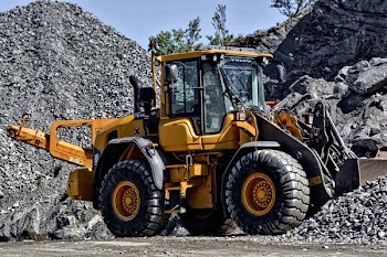 Orange and Black Tractor Next to Piles of Rocks