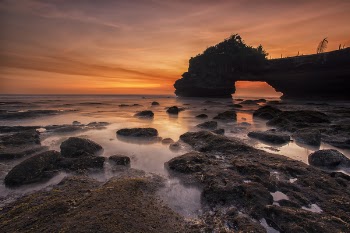 Orange and Yellow Sunset Skies over Grey Seashore Rocks and Calmed Ocean