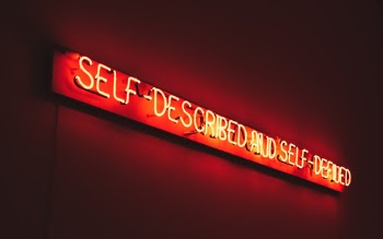 Orange neon tubes containing the message "Self-described and self-defined", a Joseph Kosuth piece found at the MAAT, Lisbon, Portugal