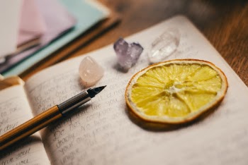 Orange Slice on top of Open Book next to a Pen