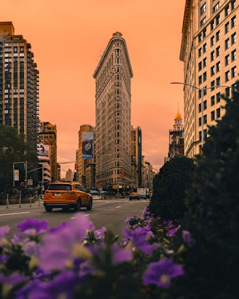Orange Vehicle on Road Near Buildings at Golden Hour