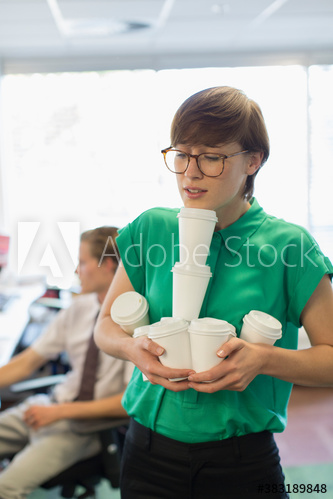 Overwhelmed businesswoman balancing coffee cups in arms