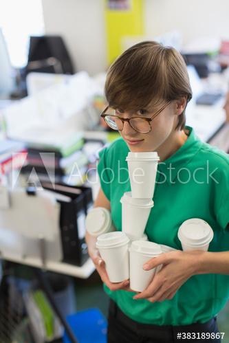 Overwhelmed businesswoman carrying armful of coffee cups