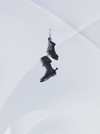 Pair of Black Boots Hanging on White Wall
