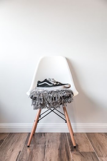 pair of black low-top Vans sneakers on white chair