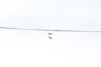 pair of green low-top sneakers hanged on wire