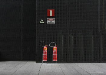 Pair of Red Fire Extinguisher Tanks in Front of Black Wall