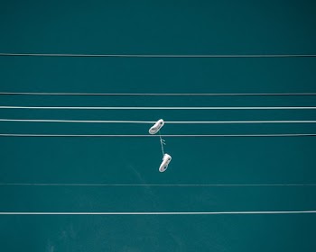 pair of white shoes hanging on cable