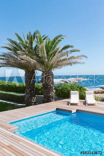 Palm trees and sunny swimming pool with ocean view