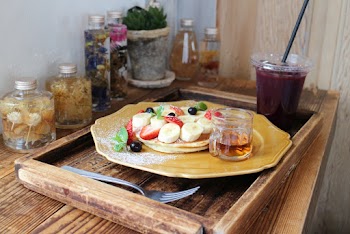 Pancakes garnished with fruits next to a Cup of juice