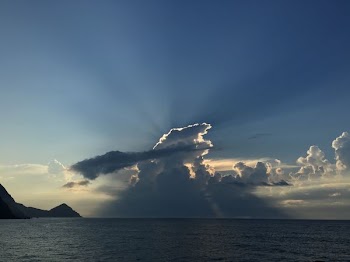 panoramic photo of sea with clouds covering the sun during daytime