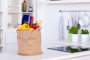 Paper shopping bag full of food on a kitchen counter