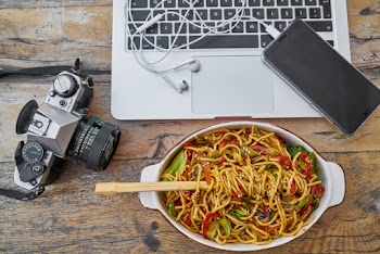 Pasta On Bowl Beside Dslr Camera And Laptop Computer