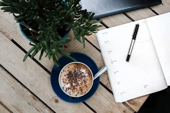 pen on printer paper beside a cappuccino