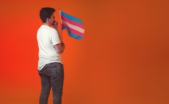 Pensive Androgyne Holding Trans Pride Banner