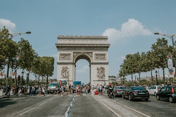 People Crossing Pathway Near Vehicles and Concrete Gate