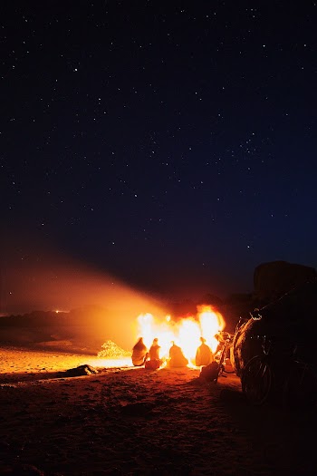 People Gathered Around A Bonfire Outdoors Under Starry  Night Sky