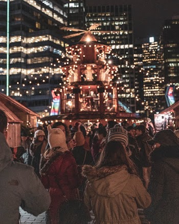 People Gathered Near Christmas Tree and Buildings at Night