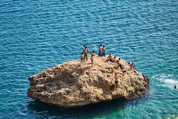 People Gathering On A Rock Formation In The Sea