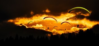 People in Mid Air Using Parachute in Dusk