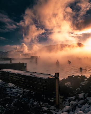 People In Water With Background View Of Sunset