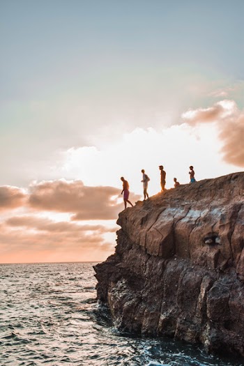 People Jumping On Body Of Water